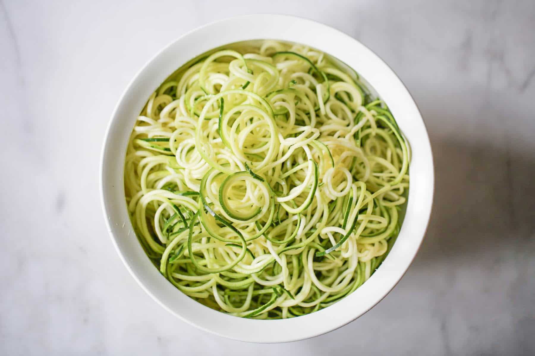 Bowl of raw spiralized zucchini noodles.
