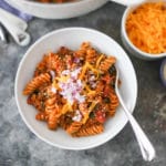 Bowl of one-pot cheeseburger pasta with toppings.
