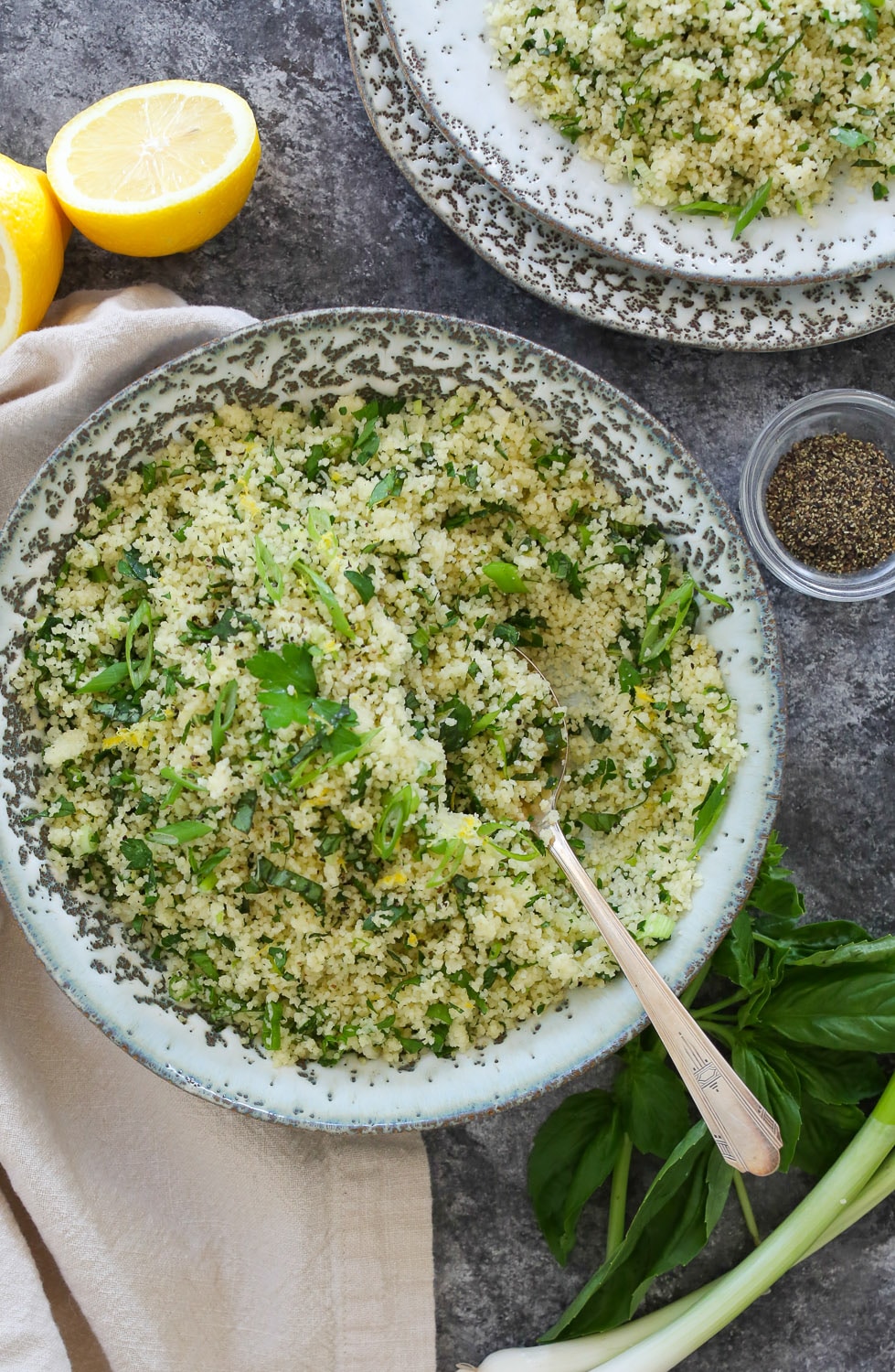Overhead close-up of Lemon-Herb Couscous with one portion taken out and put on a small side plat peeking into the upper right-hand corner.